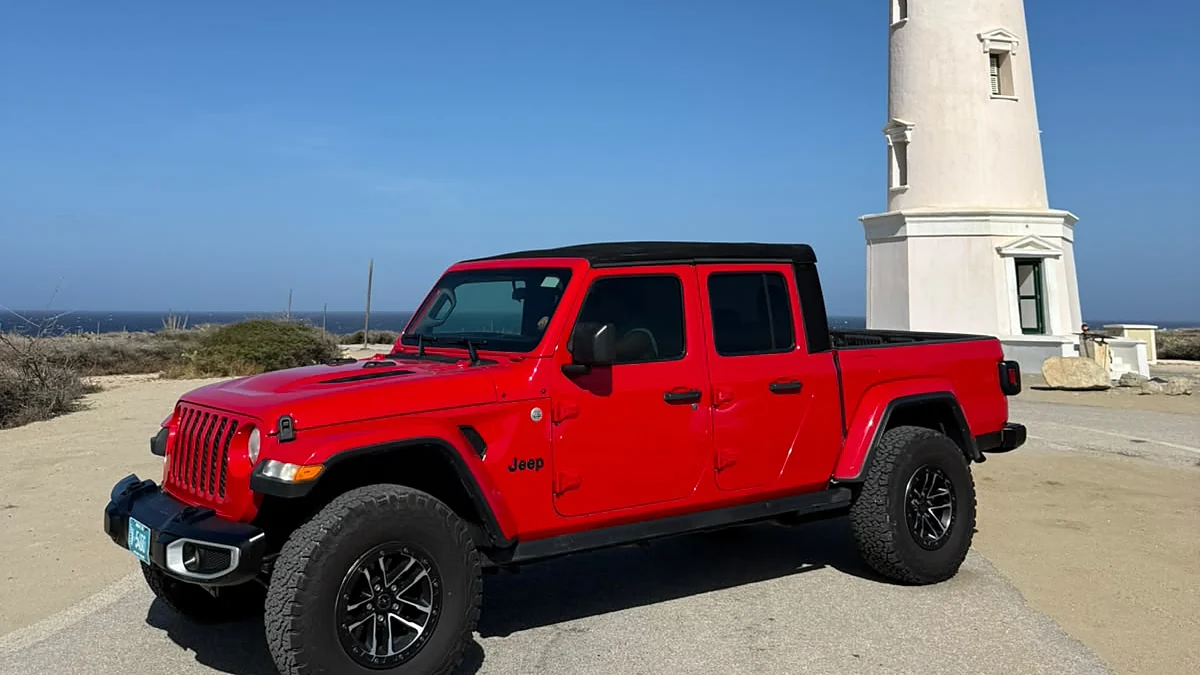 Red Aventurova Jeep Gladiator parked beside the California Lighthouse in Aruba