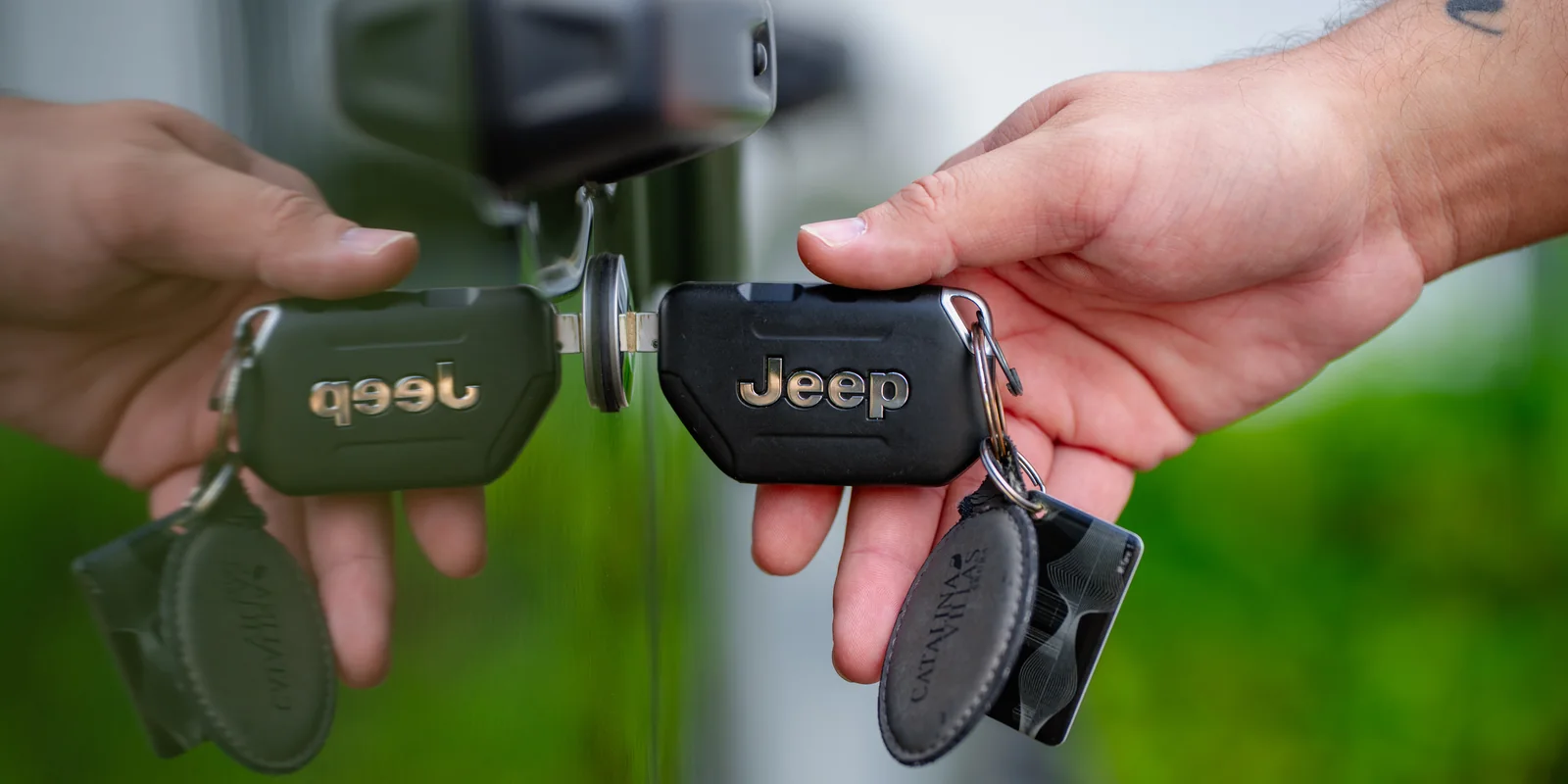 Two hands holding Jeep key fobs