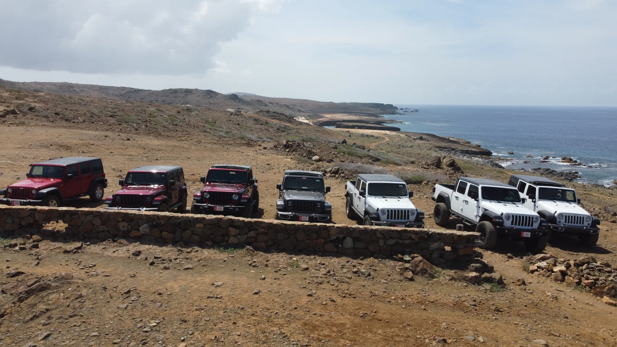 Aerial view of Aventurova Jeeps parked in a line above the coast