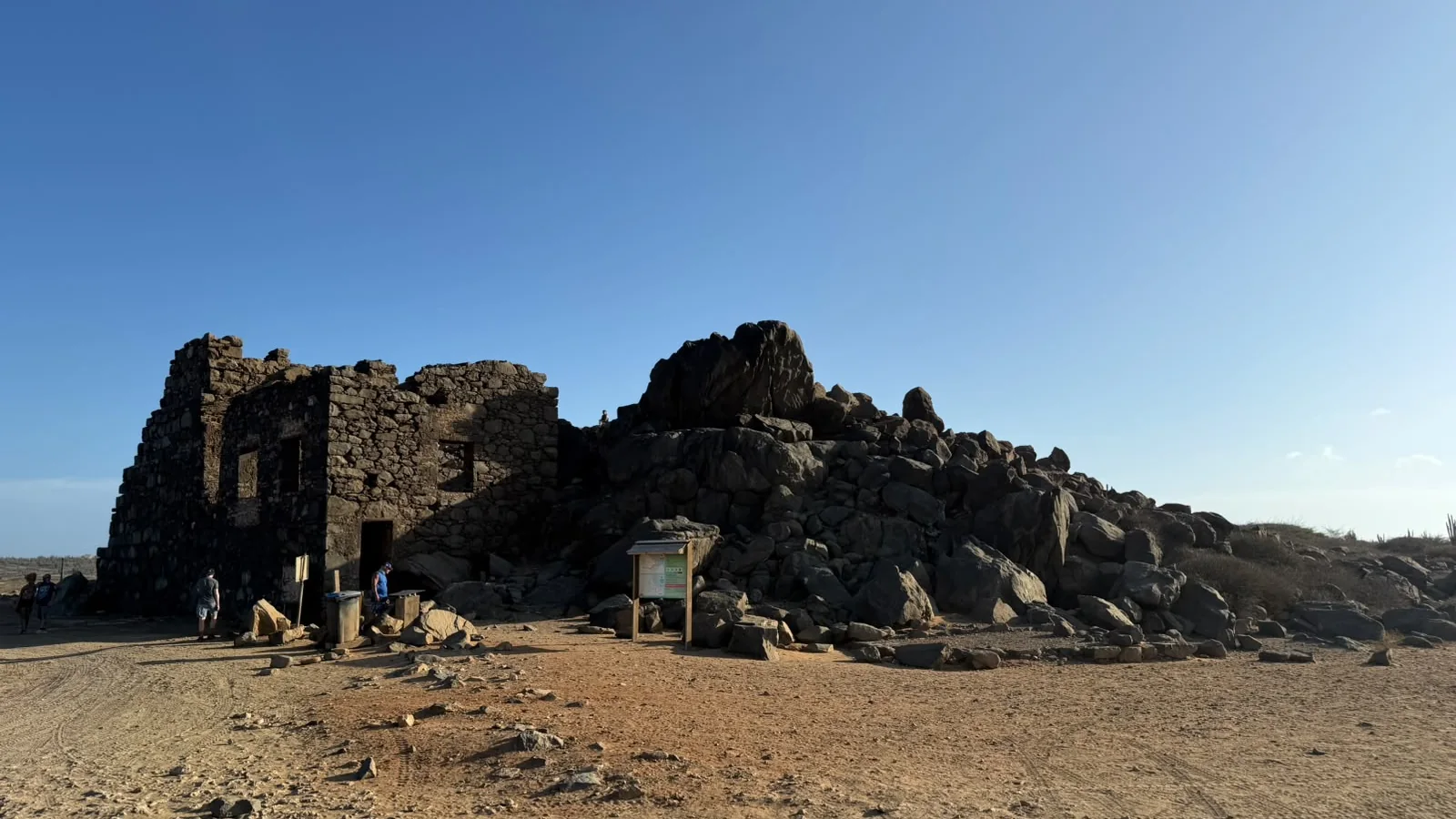 Old stone ruins on a rocky hillside under a blue sky on Aruba's north coast