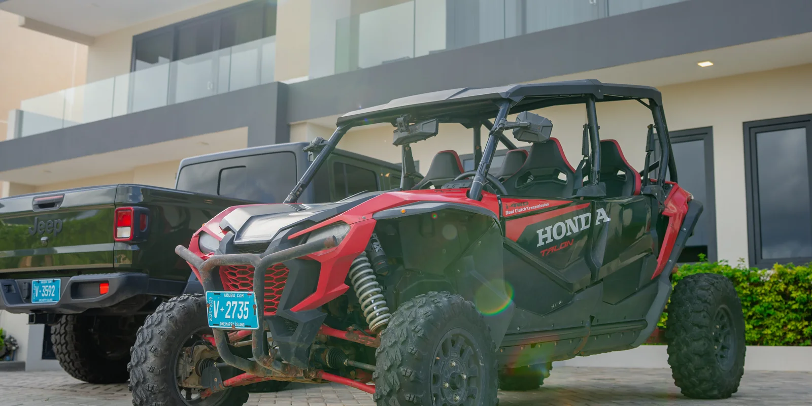 Red Honda UTV and an Aventurova Jeep Gladiator parked at a building
