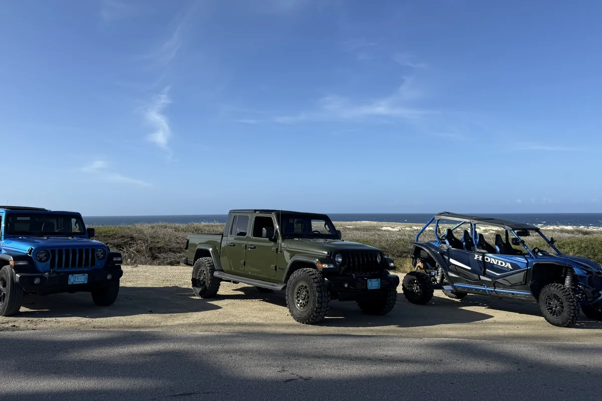 Aventurova Jeeps and a UTV parked in a row beside the coast