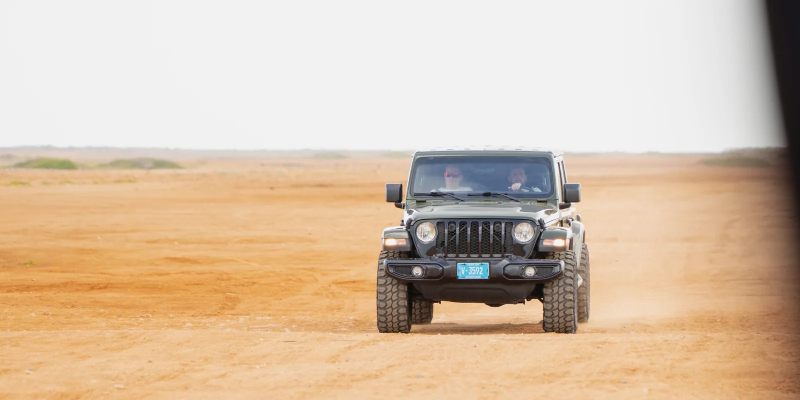 Aventurova Jeep Wrangler driving across a sandy desert track